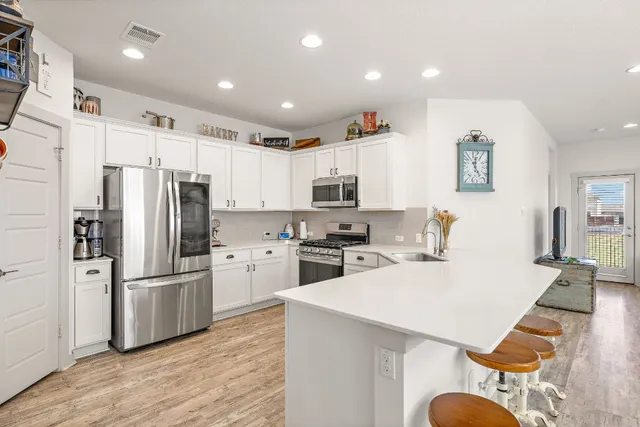 a kitchen with white cabinets and appliances