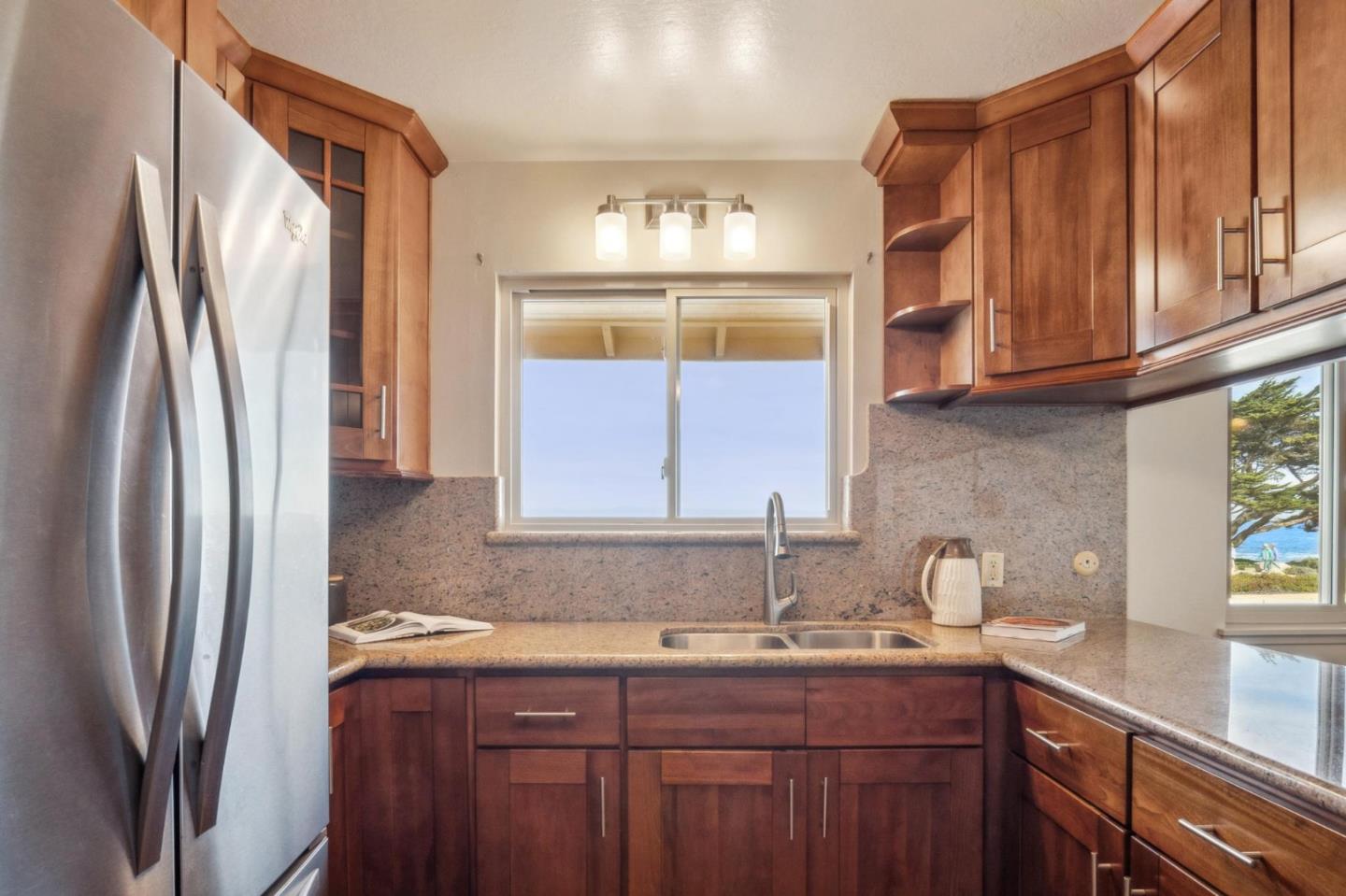 1261 Ocean View Boulevard Pacific Grove, CA 93950 - Photo 18 of 37 a kitchen with stainless steel appliances granite countertop a sink a refrigerator and wooden cabinets