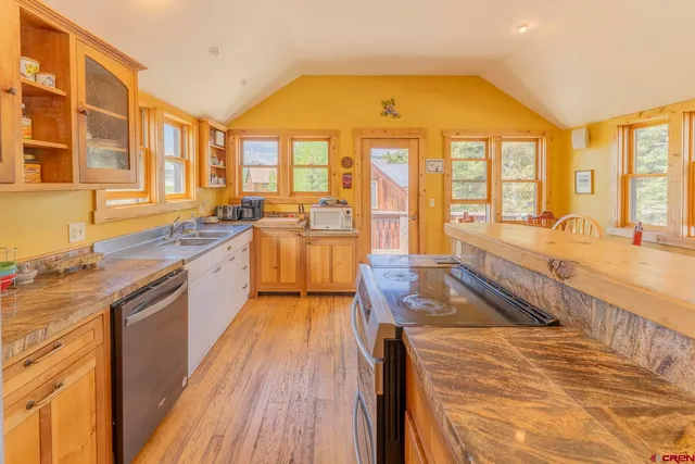 a kitchen with stainless steel appliances wooden floor a sink and a refrigerator