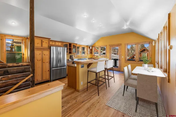 a kitchen with stainless steel appliances granite countertop a refrigerator a sink and wooden floors