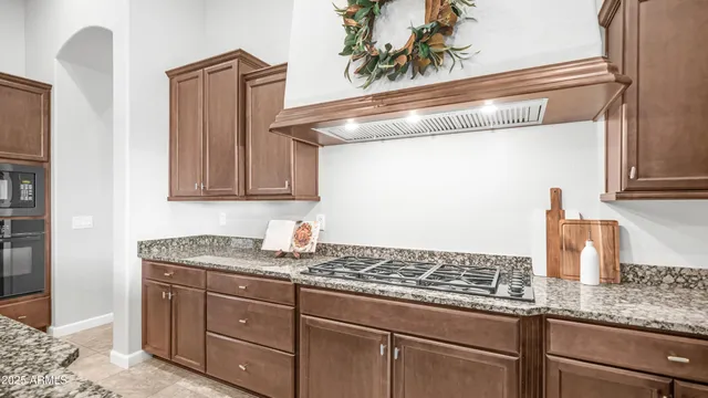 a kitchen with stainless steel appliances kitchen island granite countertop a dining table chairs and a refrigerator