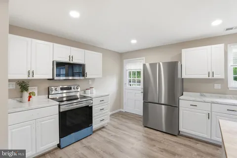 a kitchen with stainless steel appliances a refrigerator sink and white cabinets