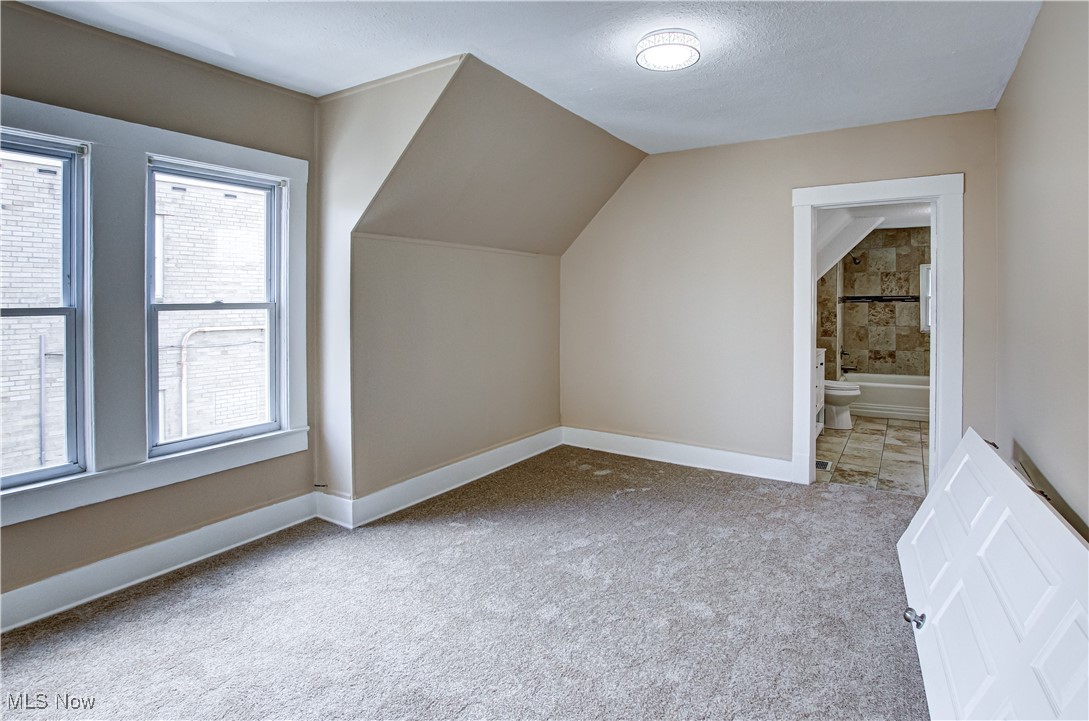 3877 Riveredge Road Cleveland, OH 44111 - Photo 22 of 27 Bonus room featuring carpet, a textured ceiling, and vaulted ceiling