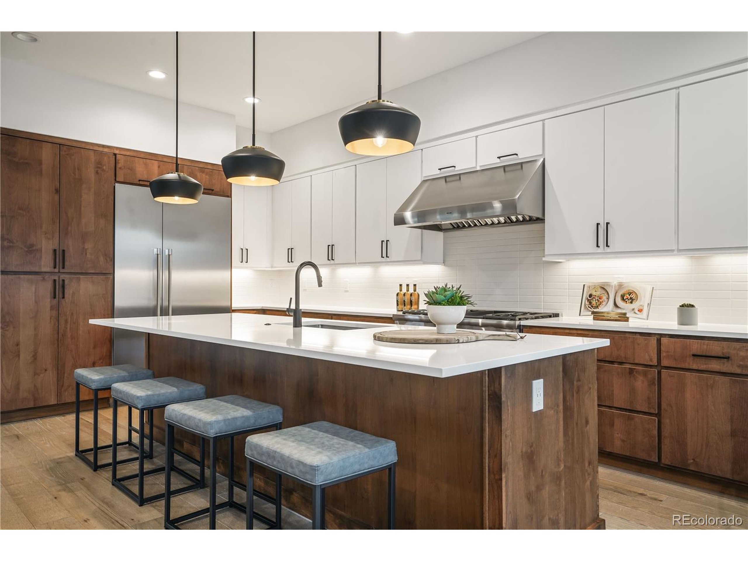 a kitchen with stainless steel appliances a sink a stove a refrigerator and chairs