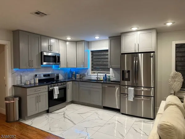 a kitchen with granite countertop a refrigerator and a stove top oven