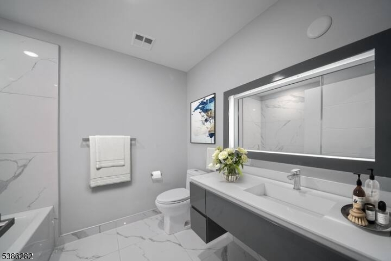 859 Main Street, Unit 40 Paterson, NJ 07503 - Photo 6 of 10 a bathroom with a granite countertop sink and a toilet