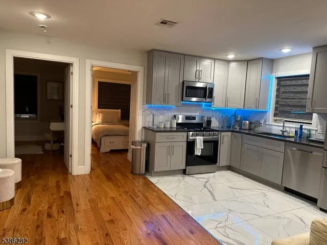 a kitchen with granite countertop a stove top oven a sink dishwasher and white cabinets with wooden floor