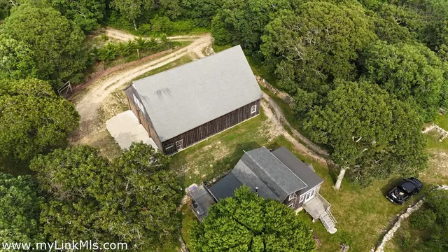 an aerial view of a house with a yard and trees all around