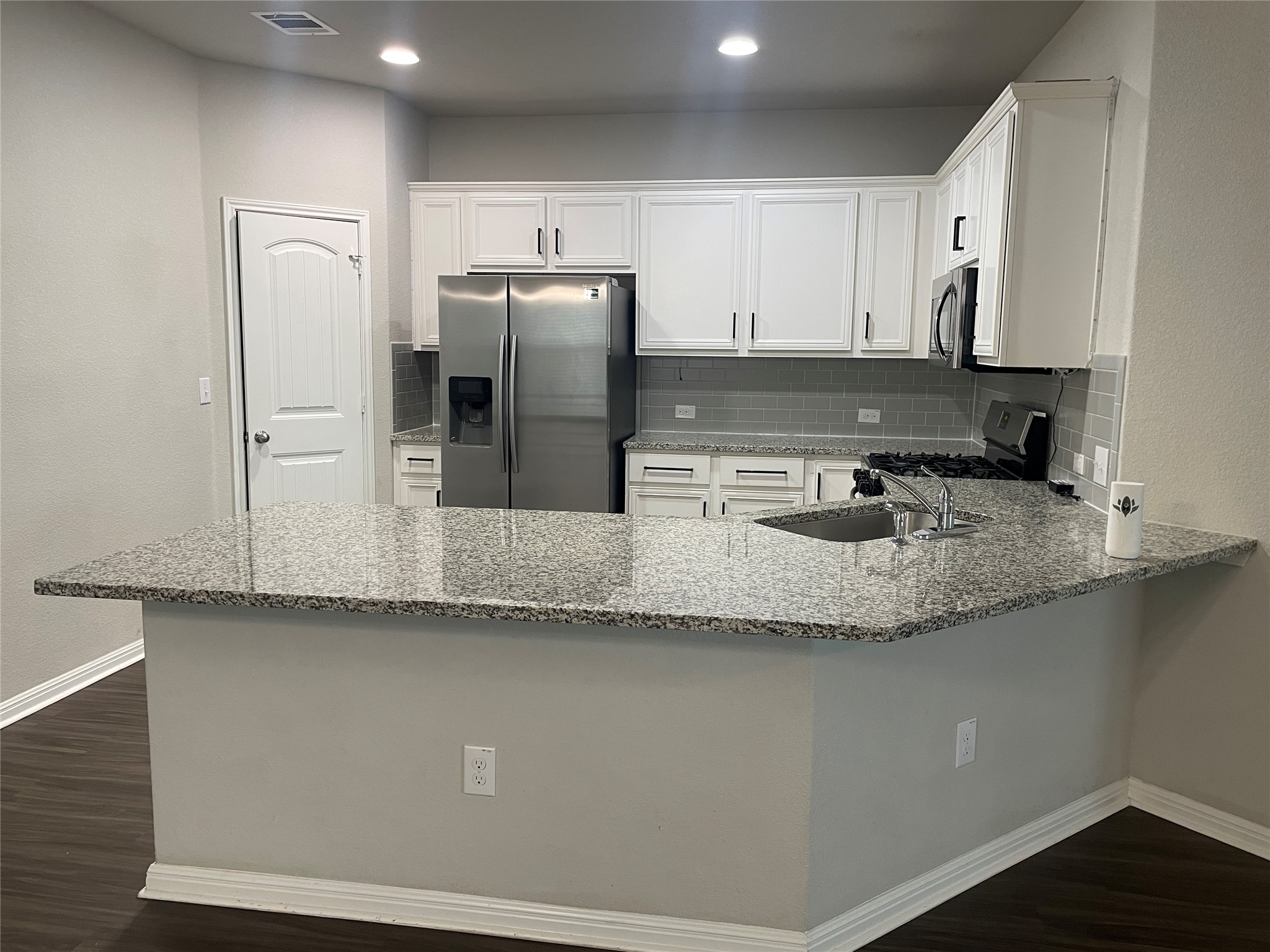 317 Bremen Street Georgetown, TX 78626 - Photo 3 of 19 a kitchen with granite countertop a refrigerator a sink and white cabinets