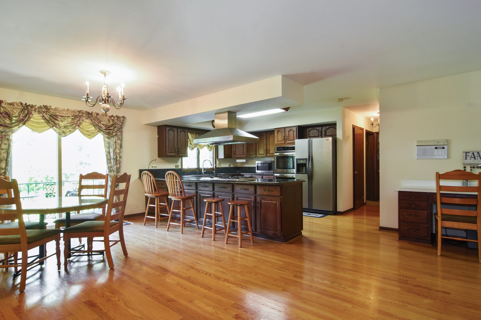 593 Scots Court Inverness, IL 60067 - Photo 8 of 15 a kitchen with stainless steel appliances kitchen island granite countertop a refrigerator a stove a dining table and chairs with wooden floor