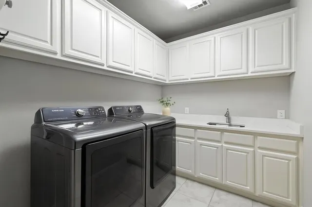 a utility room with stainless steel appliances granite countertop a sink and cabinets