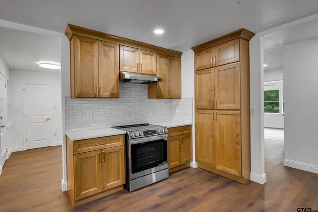 a kitchen with a stove a refrigerator and wooden floor
