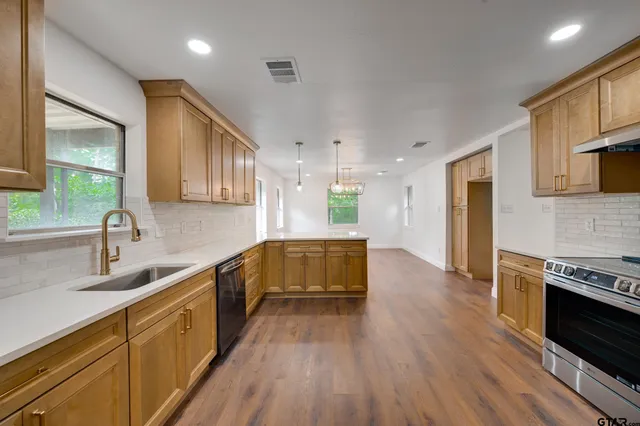 a kitchen with stainless steel appliances granite countertop wooden cabinets a stove top oven a sink and dishwasher