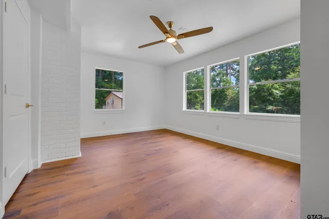 an empty room with a window and a ceiling fan