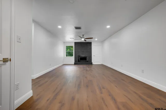 an empty room with wooden floor a fireplace and windows