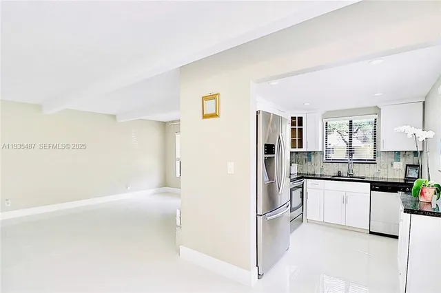 a kitchen with stainless steel appliances a refrigerator and white cabinets