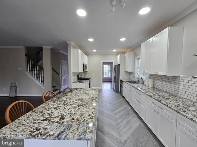 a living room with stainless steel appliances kitchen island granite countertop a sink and cabinets