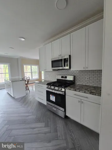 a kitchen with granite countertop a stove a sink and a microwave