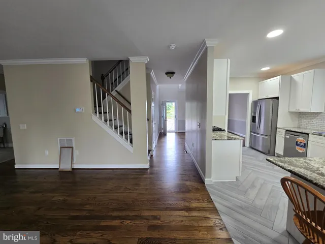 a view of a living room with wooden floor and a kitchen