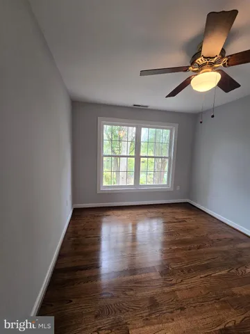 an empty room with wooden floor fan and windows