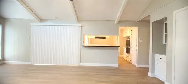 a view of a hallway to a room with wooden floor and windows