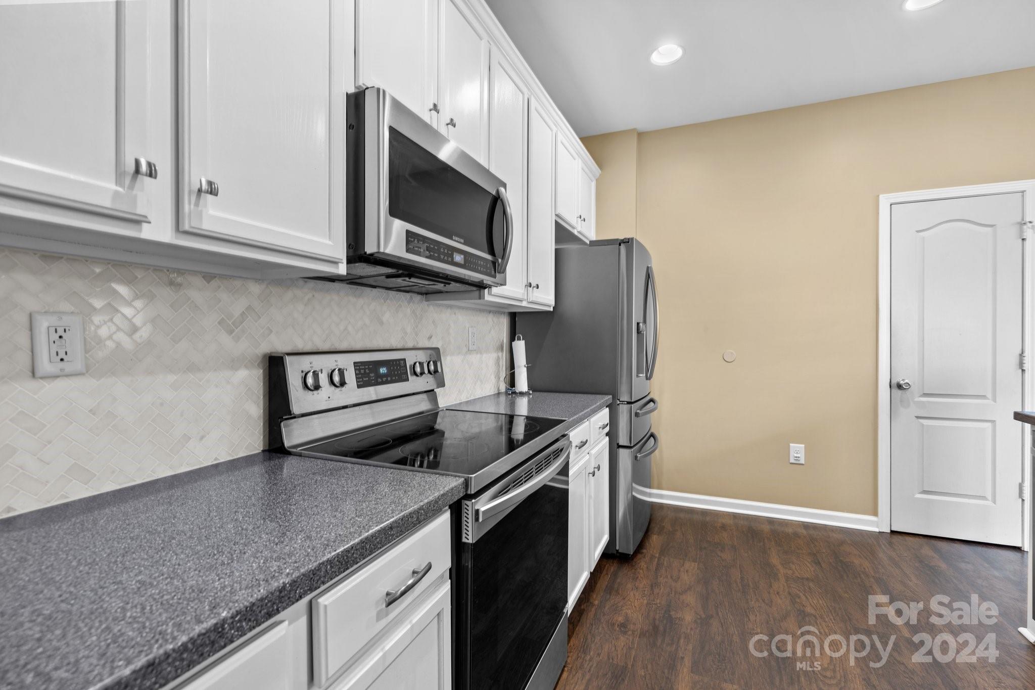 10231 Enniscrone Road Pineville, NC 28134 - Photo 18 of 44 a kitchen with stainless steel appliances granite countertop a stove a microwave and a refrigerator