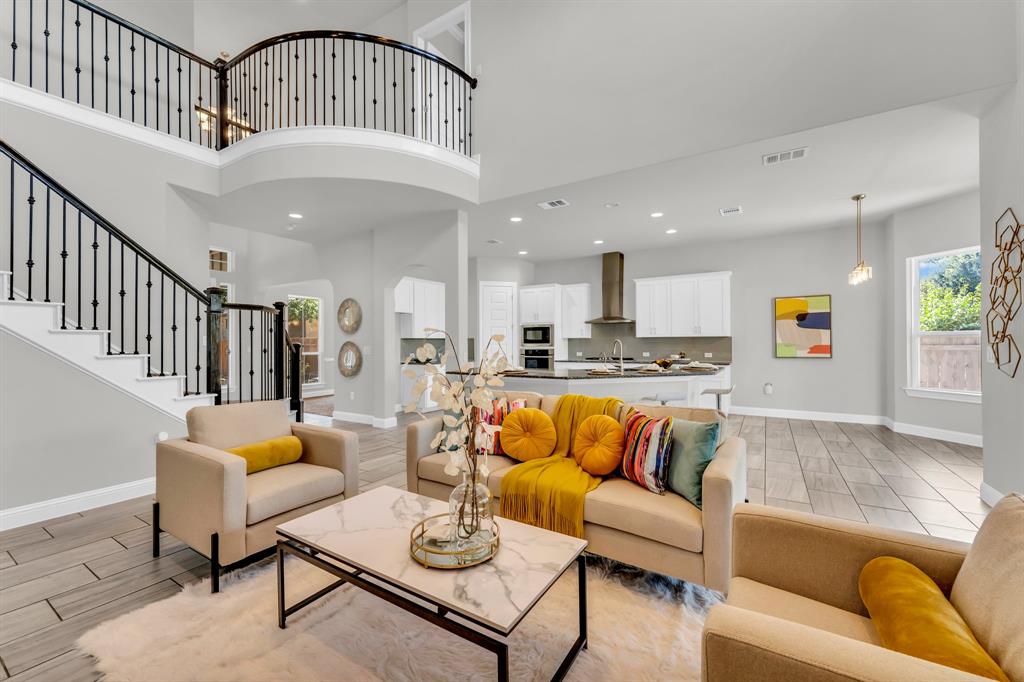 110 Magona Trail Georgetown, TX 78628 - Photo 6 of 38 A spacious living area featuring a grand staircase and an open-concept kitchen beyond.