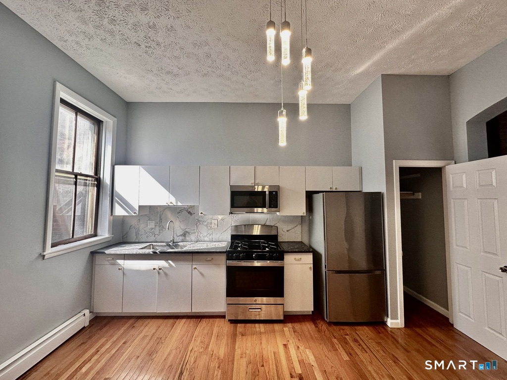 46 Warren Street New Haven, CT 06511 - Photo 6 of 10 a kitchen with a refrigerator a stove a microwave and wooden floor