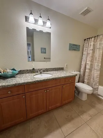 a bathroom with a granite countertop sink a toilet and shower