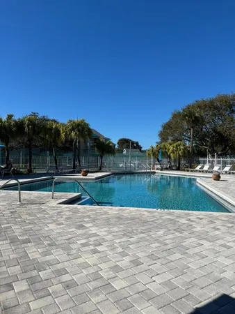 a view of a swimming pool with a patio and a backyard