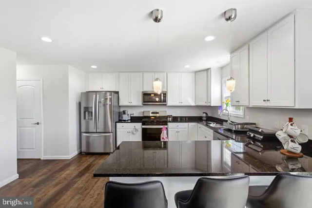 a kitchen with kitchen island a counter top space a sink stainless steel appliances and cabinets