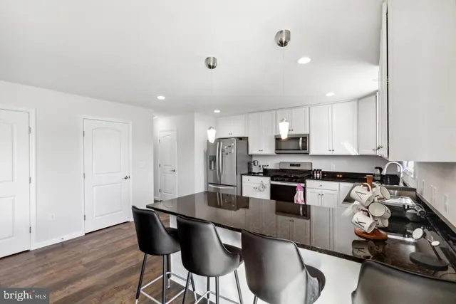 a kitchen with a dining table chairs and wooden floor