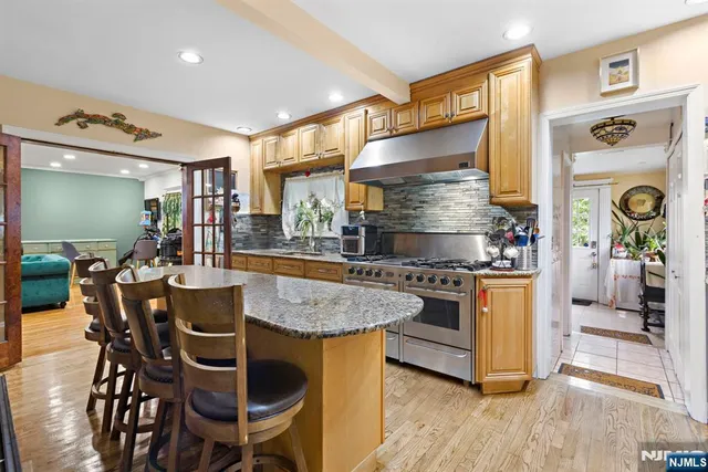 a kitchen with stainless steel appliances granite countertop dining table chairs and wooden floor