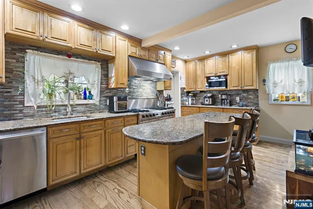 a kitchen with stainless steel appliances granite countertop table chairs sink and cabinets