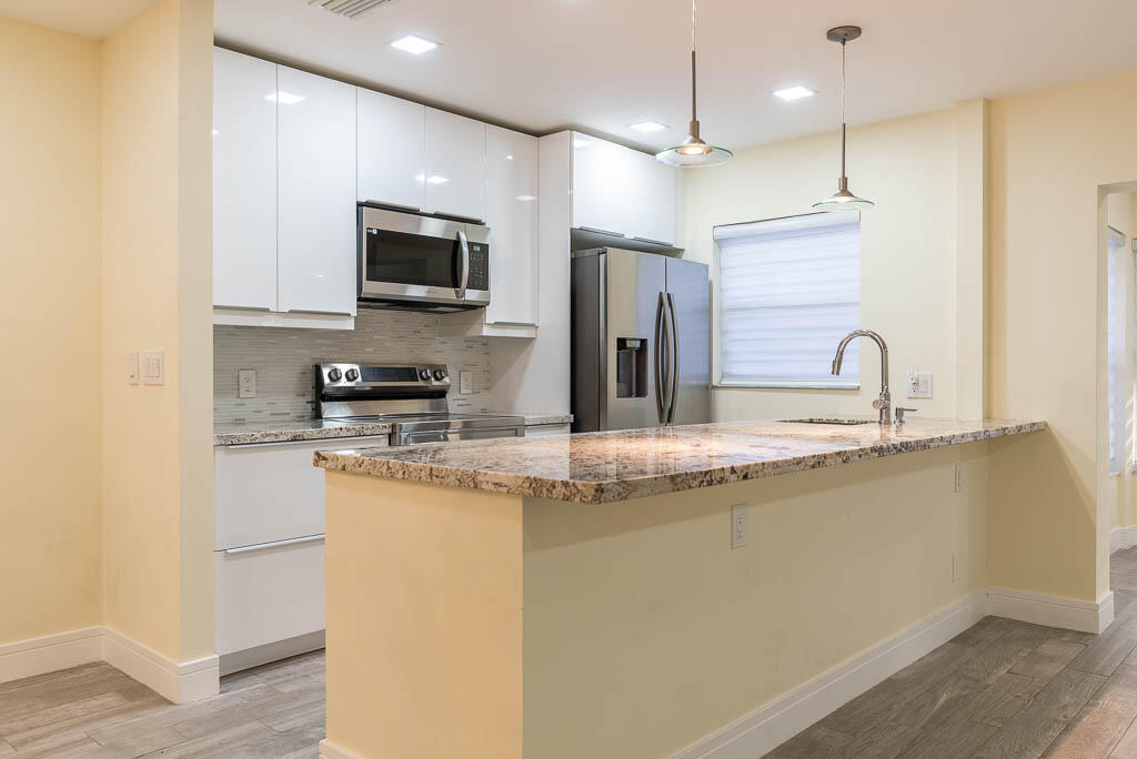 14250 Nesting Way, Unit B Delray Beach, FL 33484 - Photo 13 of 45 a kitchen with stainless steel appliances granite countertop a sink a stove and a refrigerator