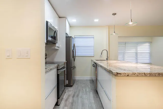 a kitchen with granite countertop cabinets stainless steel appliances a sink and a window