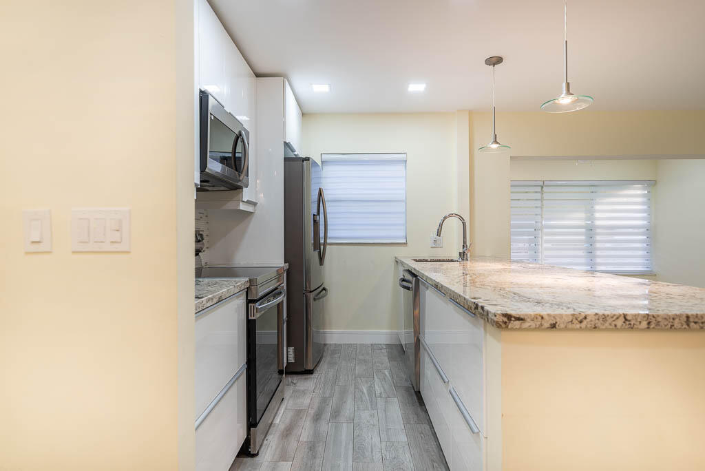 14250 Nesting Way, Unit B Delray Beach, FL 33484 - Photo 14 of 45 a kitchen with granite countertop a sink and stainless steel appliances