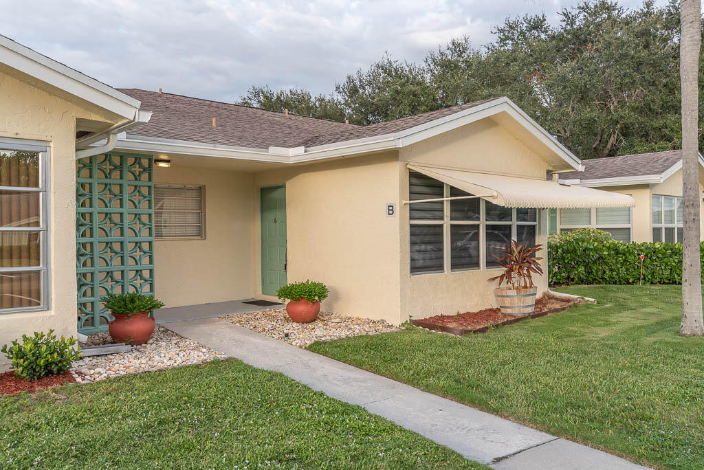 14250 Nesting Way, Unit B Delray Beach, FL 33484 - Photo 3 of 45 a front view of a house with a yard and potted plants