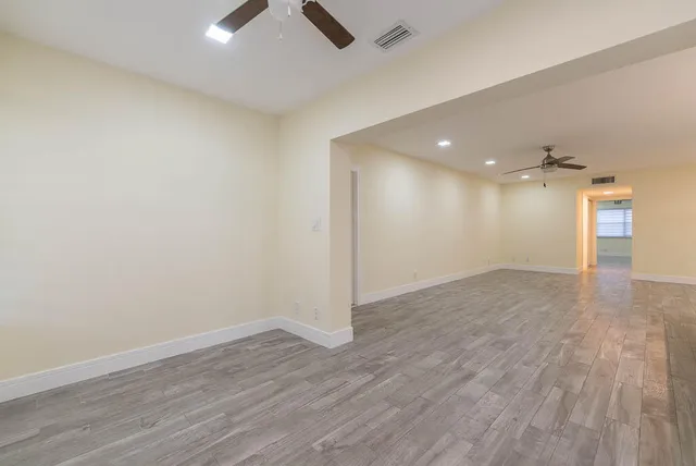 a view of kitchen and empty room with wooden floor