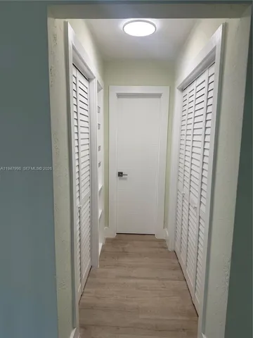 a view of a hallway with wooden floor and closet