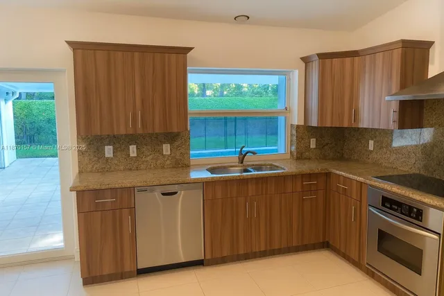 a kitchen with stainless steel appliances granite countertop wooden cabinets a sink and a stove