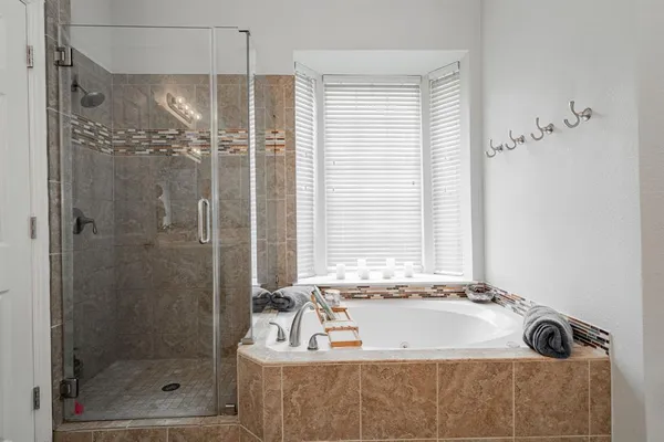 a bathroom with a tub a window and a shower