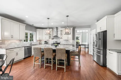a kitchen with a dining table chairs wooden floor cabinets and appliances