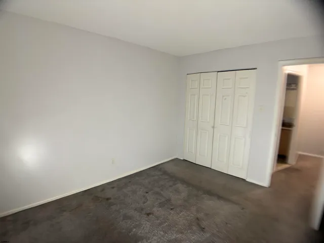 an empty room with wooden floor and closet area