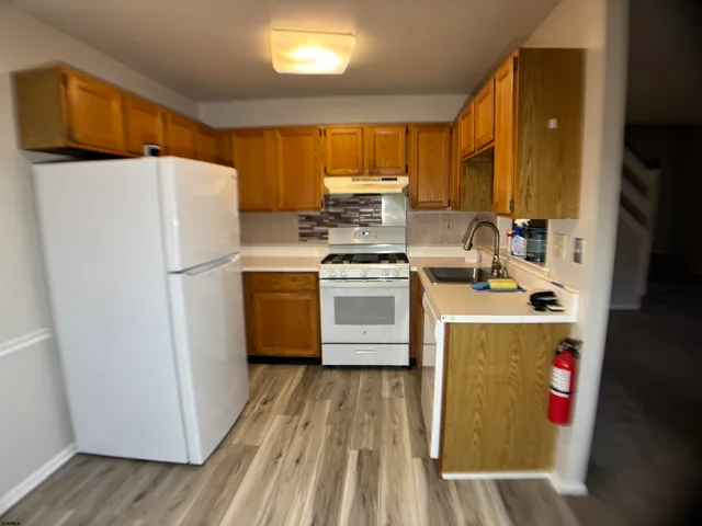 a kitchen with a refrigerator a stove and wooden floor