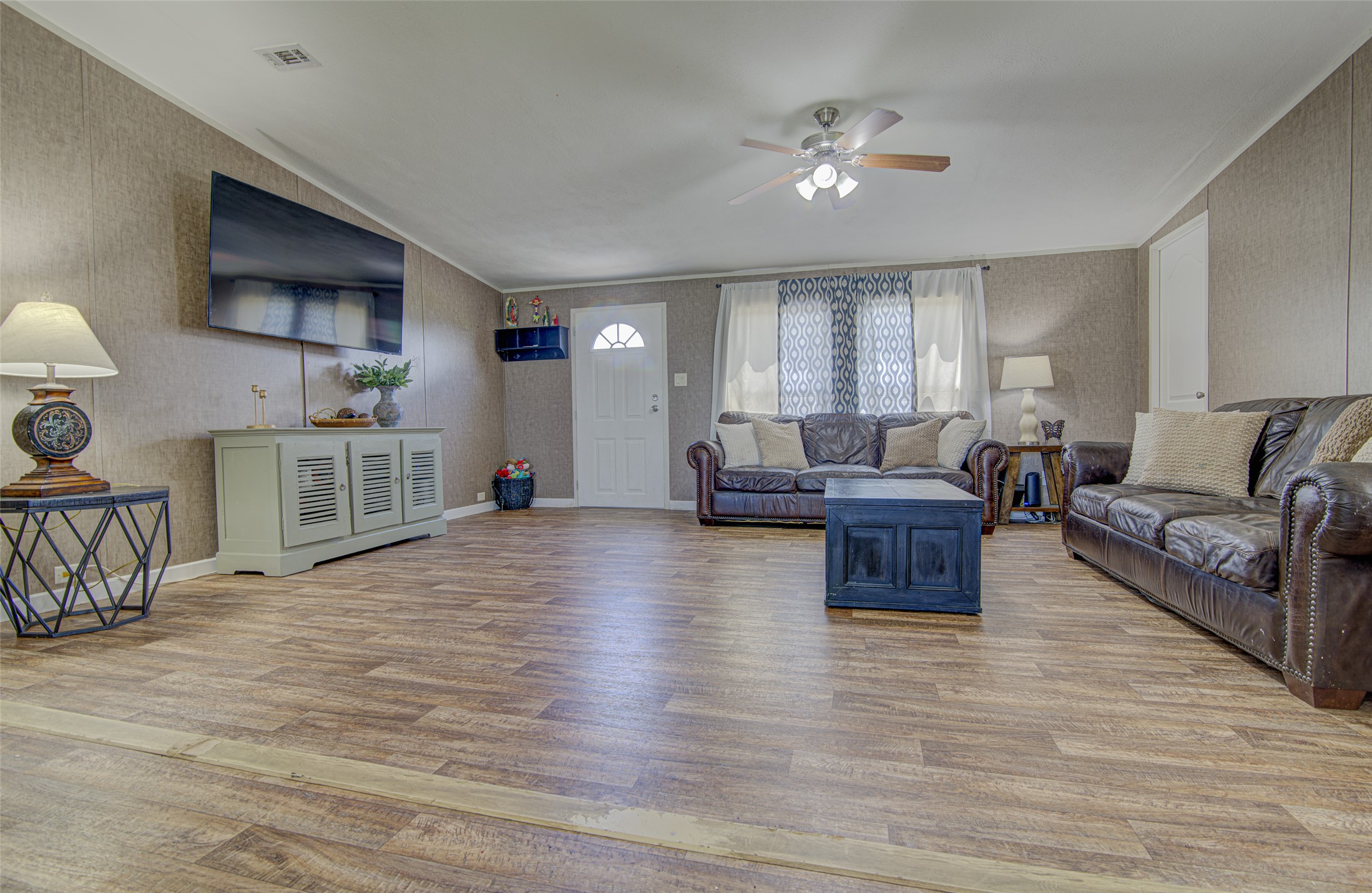 445 Rancho Linda Drive Lockhart, TX 78644 - Photo 11 of 26 A well-lit gathering space features wood flooring and a refreshing ceiling fan.