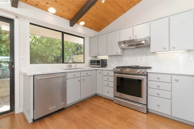 a kitchen with stainless steel appliances white cabinets and a stove top oven