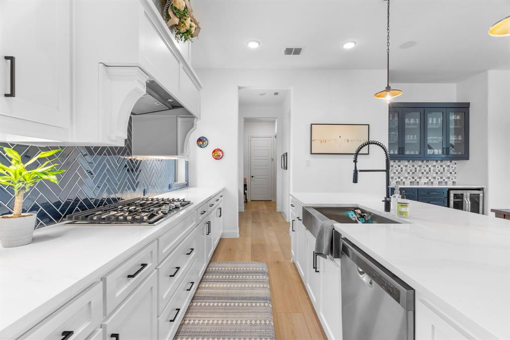 1898 Tumblegrass Road Frisco, TX 75033 - Photo 12 of 40 a kitchen with stainless steel appliances a sink a stove and a wooden floors