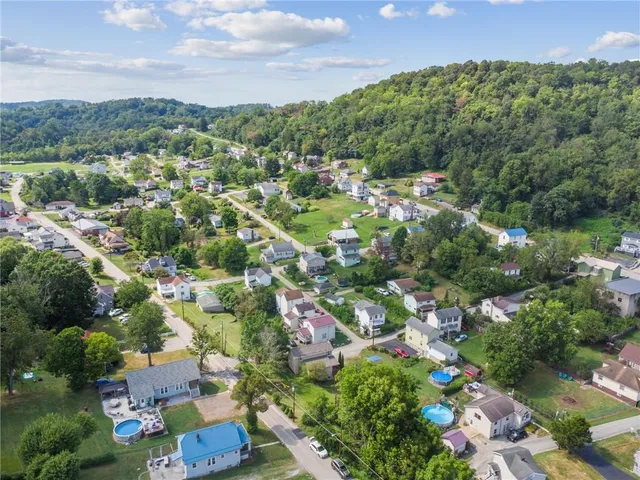 an aerial view of residential houses with outdoor space and trees