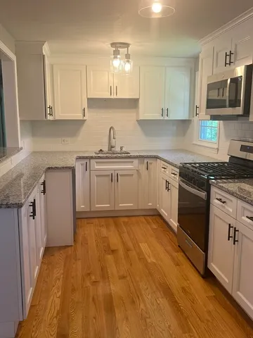a kitchen with granite countertop a sink cabinets stainless steel appliances and a counter space